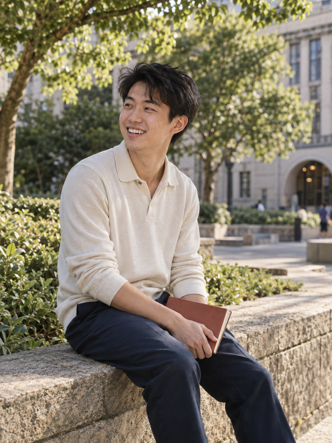 Concept photograph of a young specialist sitting sideways on a campus wall, laughing with someone off-camera